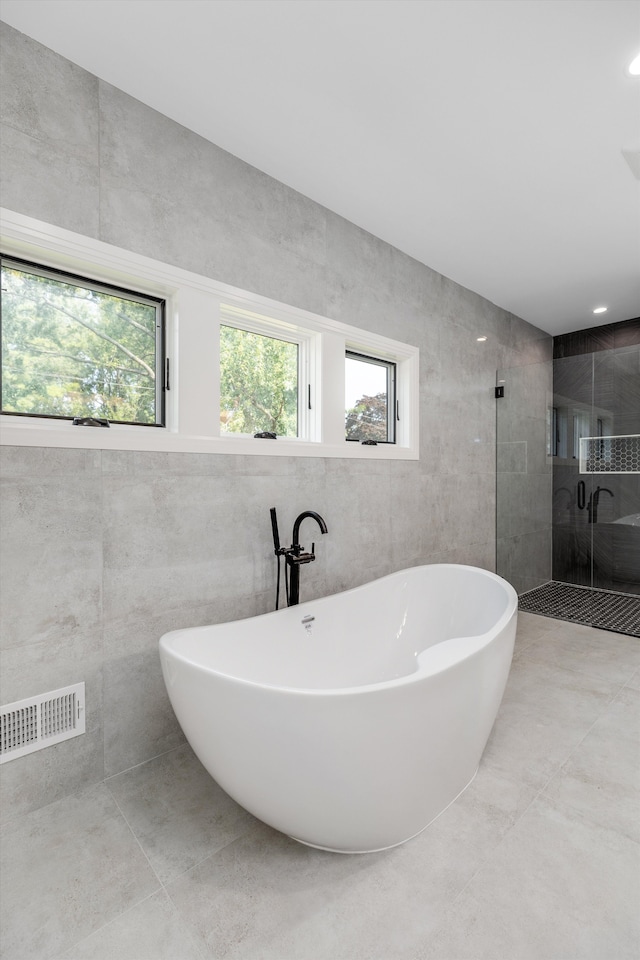 bathroom featuring shower with separate bathtub, plenty of natural light, and tile walls