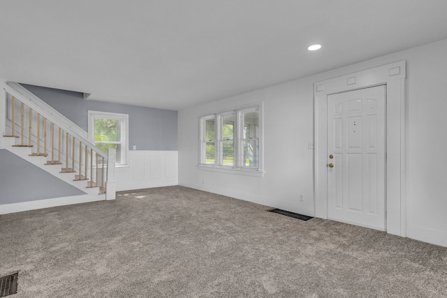 unfurnished living room with carpet flooring and plenty of natural light