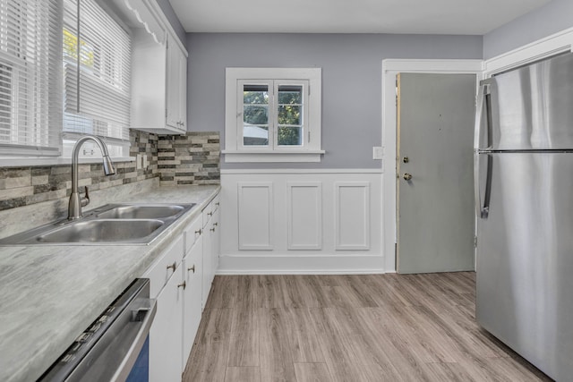 kitchen with sink, tasteful backsplash, light hardwood / wood-style floors, white cabinets, and appliances with stainless steel finishes