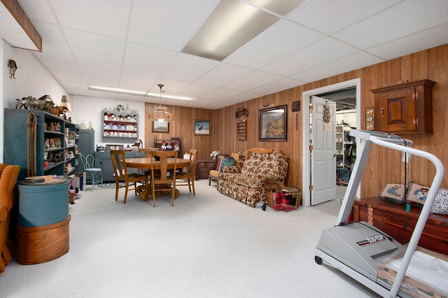 interior space featuring wooden walls and a drop ceiling