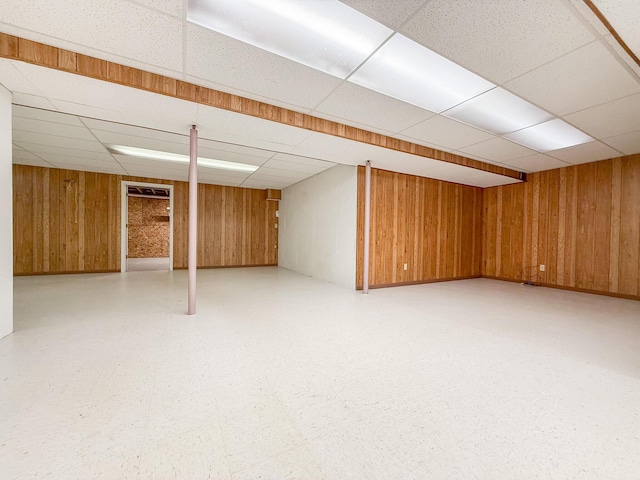 basement with a paneled ceiling and wooden walls