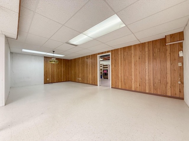 basement with a paneled ceiling and wooden walls