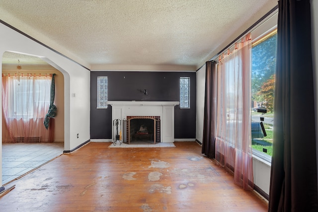 unfurnished living room with a fireplace, a textured ceiling, and light hardwood / wood-style floors