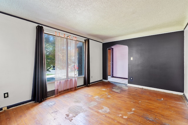 unfurnished room featuring light wood-type flooring, a textured ceiling, and a wealth of natural light