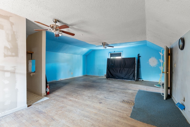 additional living space featuring wood-type flooring, a textured ceiling, ceiling fan, and lofted ceiling