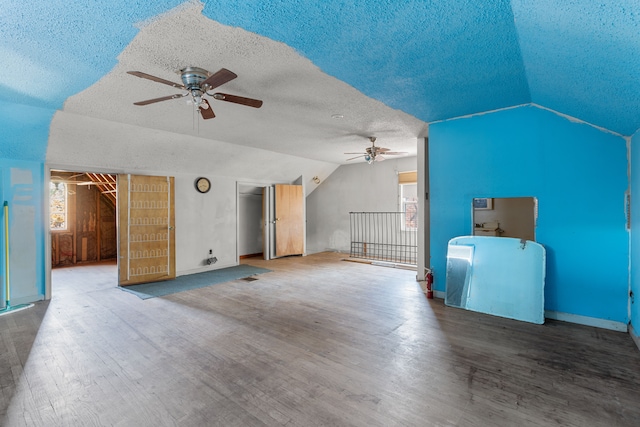 unfurnished living room featuring vaulted ceiling, ceiling fan, hardwood / wood-style floors, and a textured ceiling