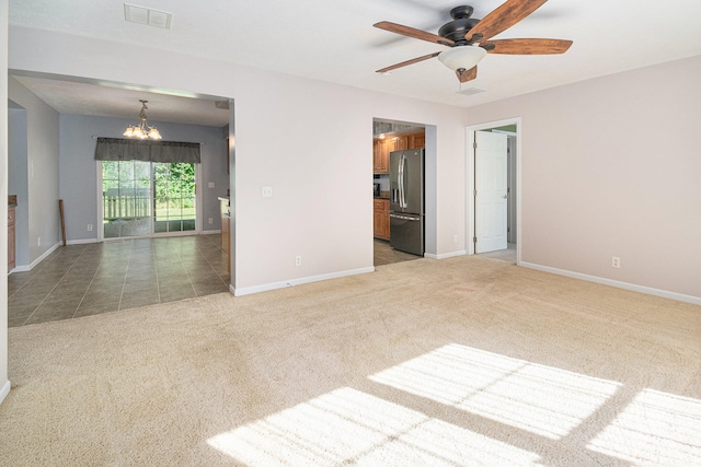 carpeted spare room with ceiling fan with notable chandelier