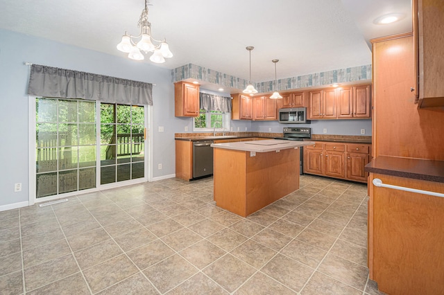 kitchen with appliances with stainless steel finishes, a kitchen island, hanging light fixtures, and a notable chandelier