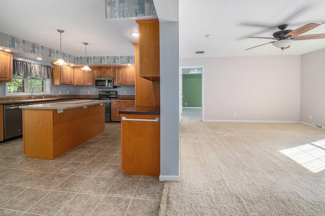 kitchen with appliances with stainless steel finishes, ceiling fan, sink, decorative light fixtures, and a center island