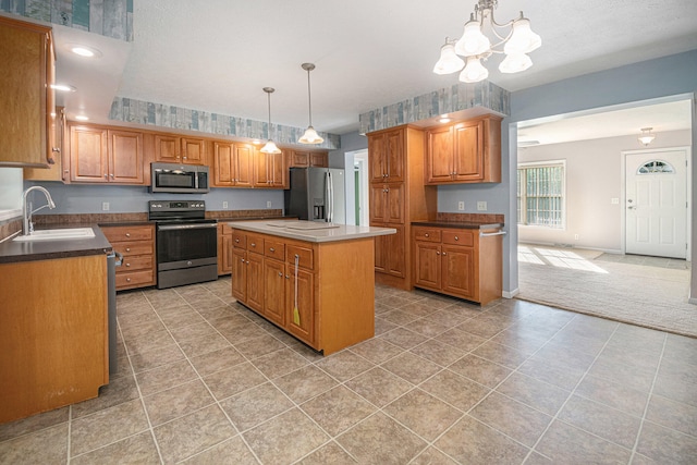 kitchen featuring stainless steel appliances, sink, pendant lighting, a chandelier, and a center island