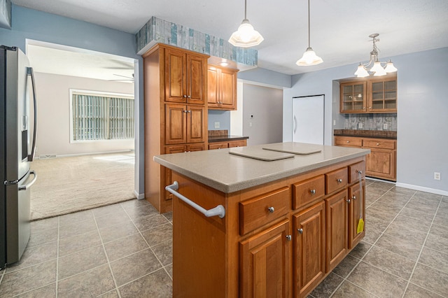 kitchen featuring decorative light fixtures, a center island, dark tile patterned floors, and stainless steel refrigerator with ice dispenser