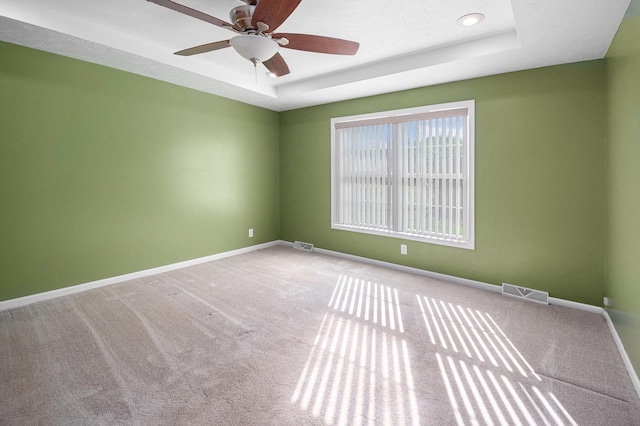 unfurnished room with a tray ceiling, ceiling fan, and carpet flooring