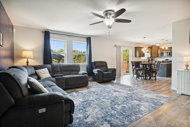 living room featuring light hardwood / wood-style floors and ceiling fan with notable chandelier