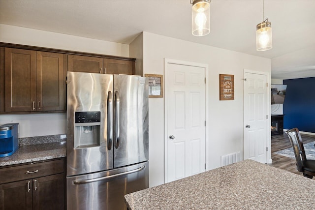 kitchen featuring decorative light fixtures, stainless steel refrigerator with ice dispenser, light stone countertops, and dark brown cabinetry