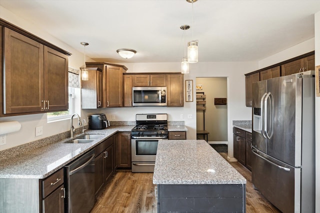 kitchen featuring light stone countertops, pendant lighting, stainless steel appliances, sink, and dark hardwood / wood-style floors