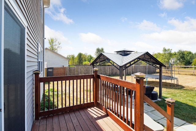 wooden terrace featuring a gazebo, a yard, and a trampoline