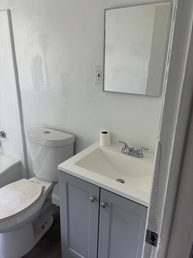 bathroom with a bath, vanity, and toilet