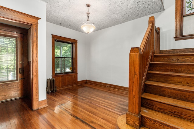 3937 Avery St, Detroit, MI 48208 - spare room with radiator, hardwood / wood-style floors, stairs, baseboards, and a textured ceiling