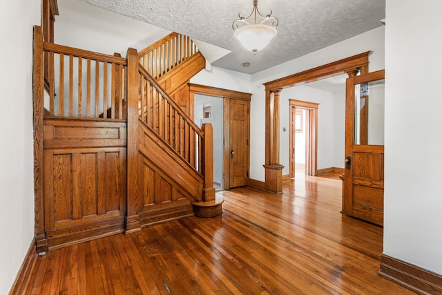 entryway with hardwood / wood-style flooring, a textured ceiling, and decorative columns