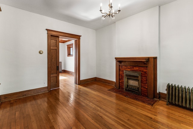 unfurnished living room with radiator, a fireplace, a chandelier, and hardwood / wood-style flooring