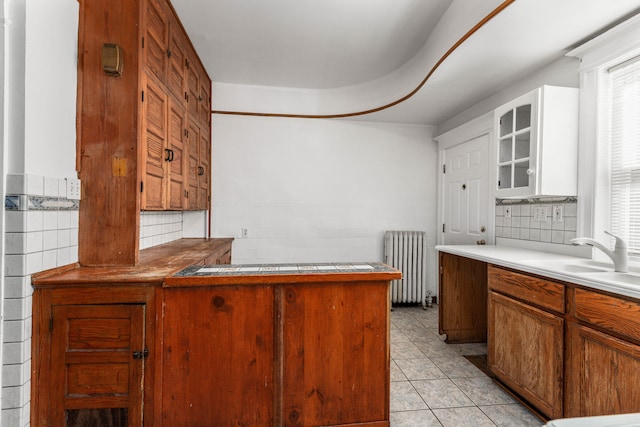 3937 Avery St, Detroit, MI 48208 - kitchen with radiator, a sink, glass insert cabinets, decorative backsplash, and light tile patterned floors
