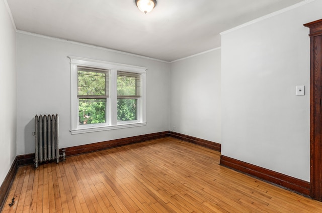 spare room featuring light hardwood / wood-style floors, radiator heating unit, and ornamental molding