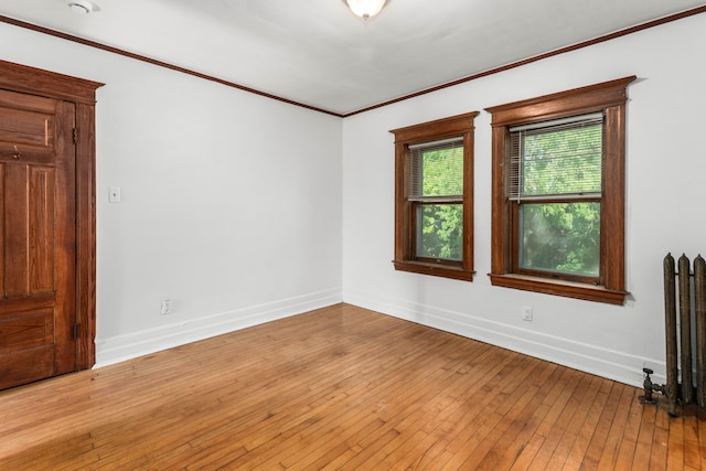 unfurnished room featuring radiator, ornamental molding, and light wood-type flooring