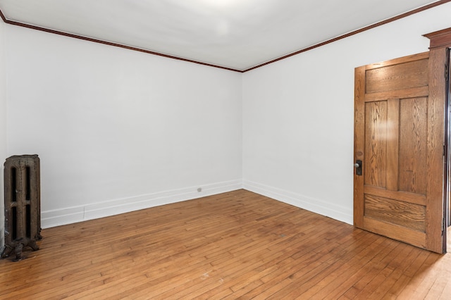 spare room featuring light wood-type flooring, radiator, and crown molding