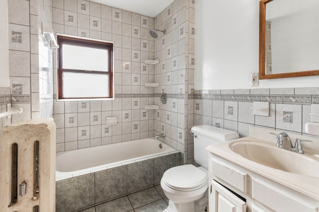 full bathroom featuring tile patterned floors, vanity, tiled shower / bath combo, tile walls, and toilet