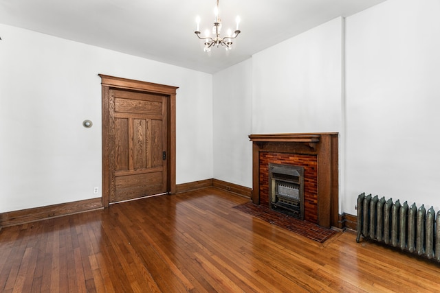 unfurnished living room featuring radiator heating unit, wood-type flooring, and a notable chandelier