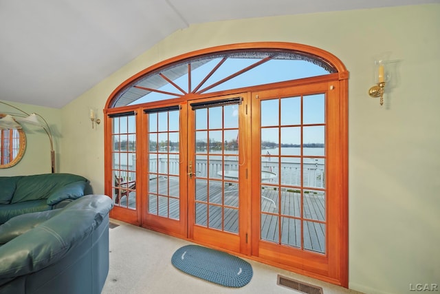 doorway to outside with a water view, light colored carpet, french doors, and vaulted ceiling