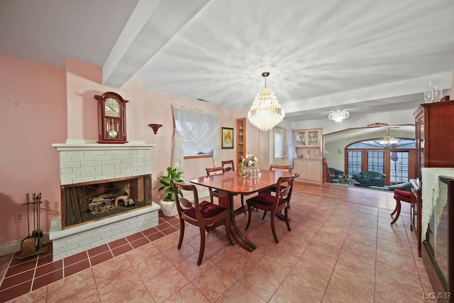 dining room featuring tile patterned floors, a chandelier, and a brick fireplace