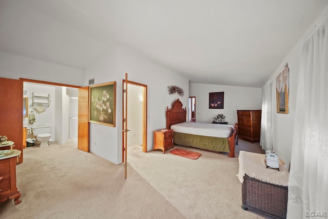 carpeted bedroom with vaulted ceiling and ensuite bath