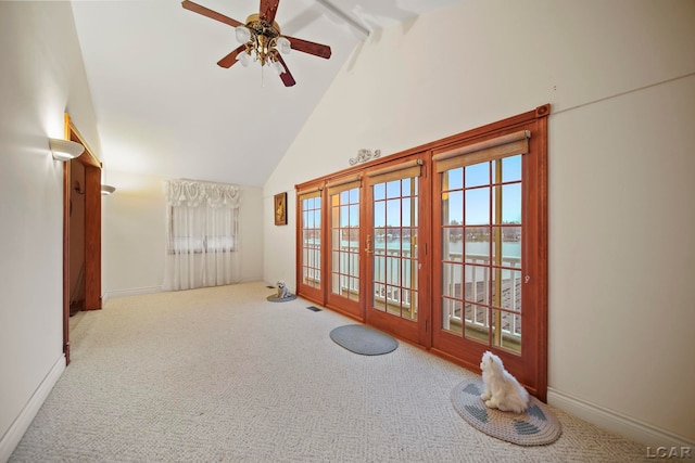 carpeted empty room featuring french doors, a water view, high vaulted ceiling, and ceiling fan