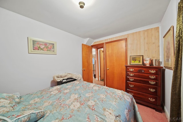 carpeted bedroom with wood walls, crown molding, and a closet