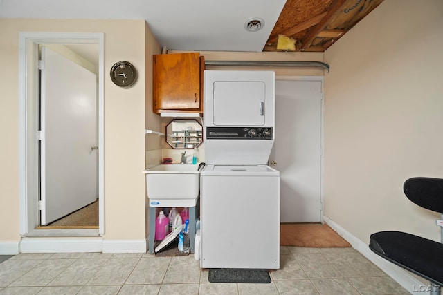 laundry room featuring sink, light tile patterned floors, and stacked washer and dryer