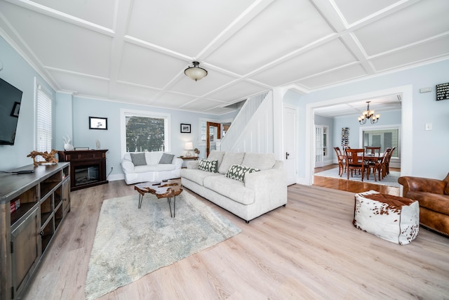 living room featuring a chandelier, light wood-type flooring, and coffered ceiling