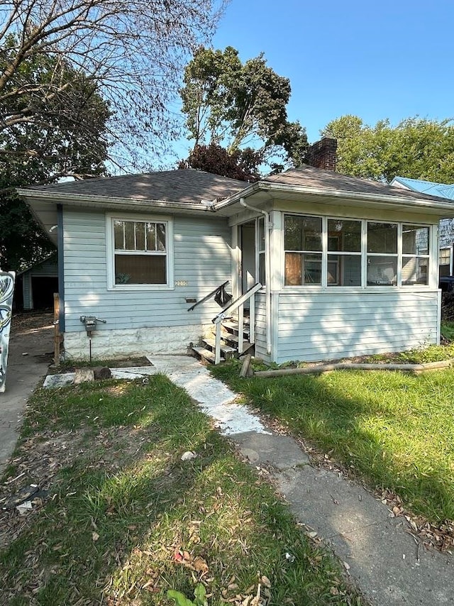 view of front of property with a sunroom and a front lawn