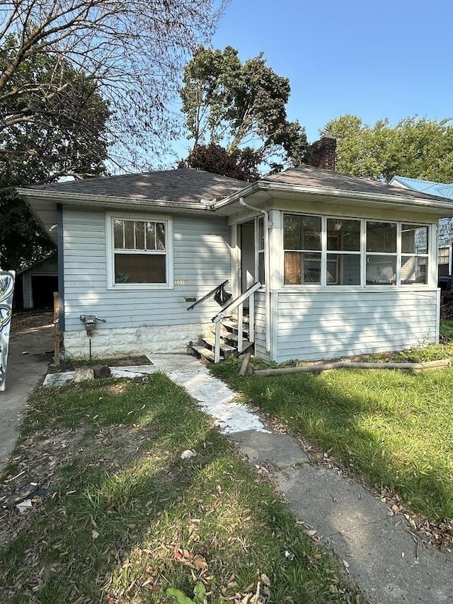 view of front of house with entry steps, a chimney, and a sunroom