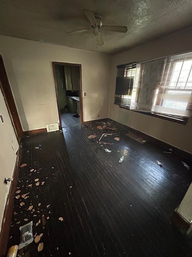 empty room featuring ceiling fan, wood-type flooring, and a textured ceiling