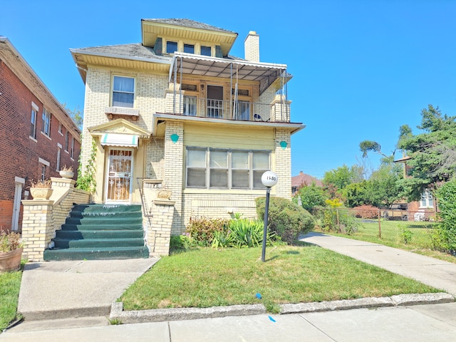 view of front of house with a balcony and a front yard