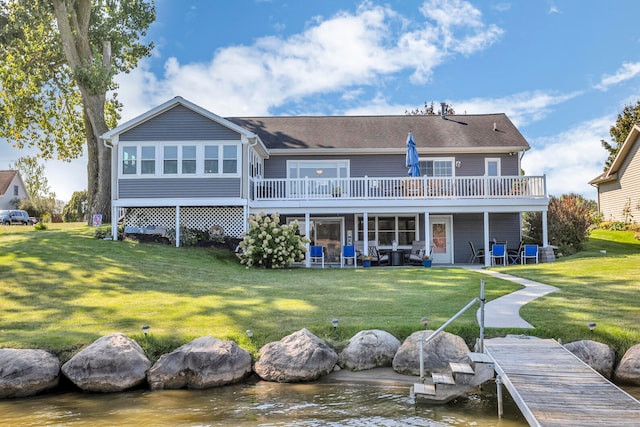 rear view of property featuring a deck with water view, a patio, and a lawn