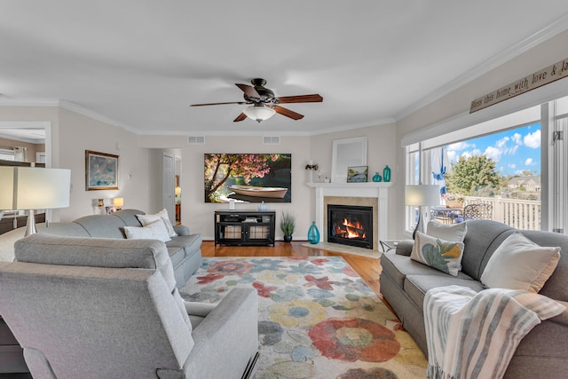 living room with ceiling fan, ornamental molding, and light hardwood / wood-style flooring