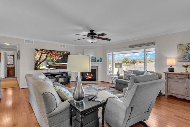 living room featuring light wood-type flooring, ornamental molding, and a wealth of natural light