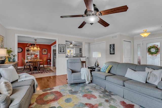 living room featuring light wood-type flooring, crown molding, and a notable chandelier