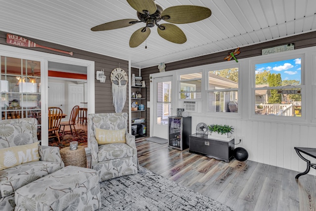 living room featuring wooden walls, hardwood / wood-style floors, ceiling fan, and beverage cooler