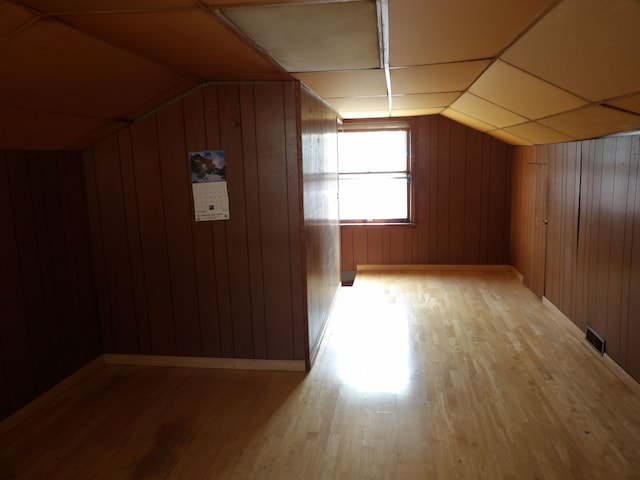 additional living space featuring wood walls, lofted ceiling, and light wood-type flooring