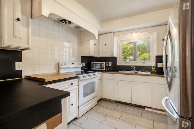 kitchen featuring wooden counters, white cabinets, sink, a textured ceiling, and stainless steel appliances