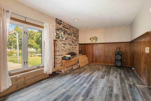 unfurnished living room with wooden walls, dark hardwood / wood-style flooring, and plenty of natural light