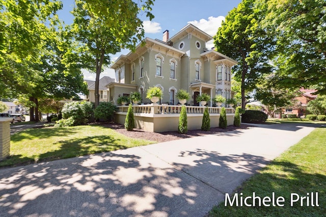 118 E Oliver St, Owosso, MI 48867 - italianate-style house featuring a fenced front yard, a chimney, and stucco siding
